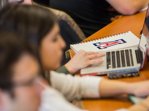 blurry image of students in class, with laptop and UArizona notebook, University of Arizona, Tucson